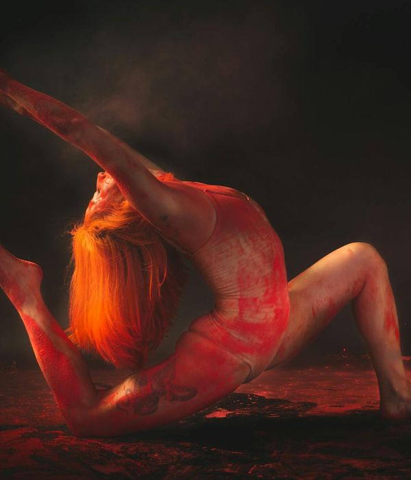 Person in an energetic yoga pose against a dark, stylish background.