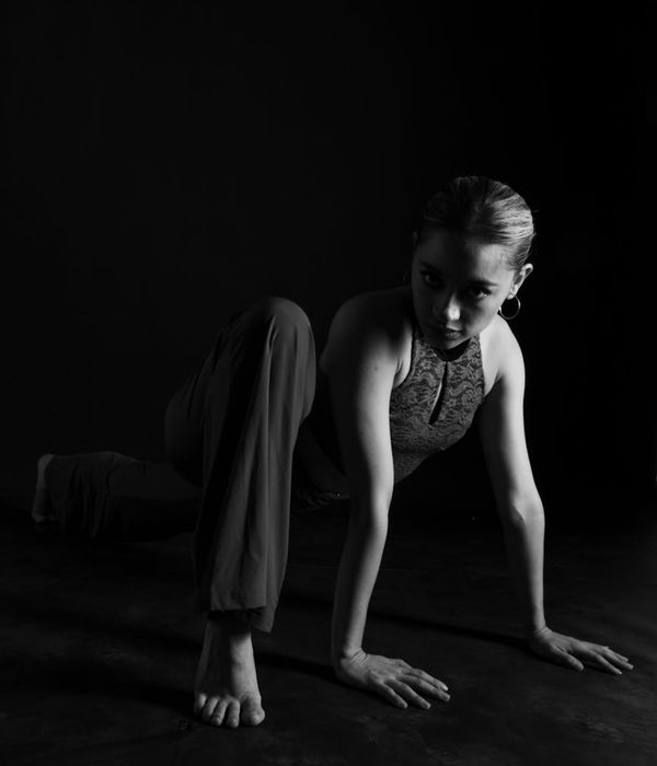 Woman performing a calm yoga pose in a dark, minimalist setting.